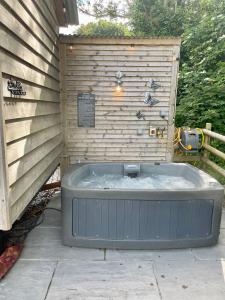 eine Badewanne neben einer Holzwand in der Unterkunft Lle Mary - Beautiful views, Hot tub, Secluded, Dog Welcome, Barmouth in Llanddwywe