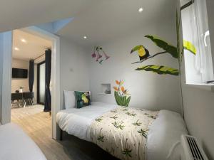 a bedroom with a bed with birds and flowers on the wall at Coastline Retreats - Brand New Jungle Themed Garden Apartment - Outdoor Bath - Next to Seafront - Childrens Toys - Superfast Wifi - Netflix - Disney in Southbourne