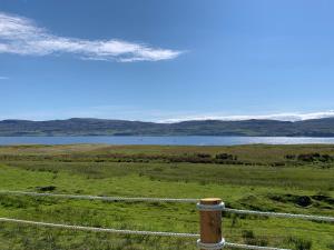 a fence in the middle of a field with a lake at Coral Cabins in Dunvegan