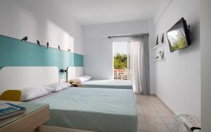 a bedroom with two beds and a tv on a wall at Kochyli Beach Studios in Nea Plagia