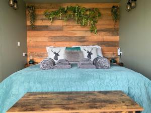 a bed with a green comforter with a wooden wall at Coral Cabins in Dunvegan
