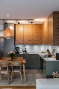 a kitchen with wooden cabinets and a table and chairs at WILANESKA Apartament Olimpijska Szczyrk in Szczyrk