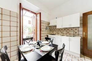 a kitchen with a black table and chairs and a kitchen with white cabinets at Apartment Colosseo in Rome