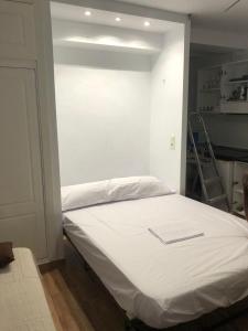 Cama blanca en habitación con escalera en Estudio cerca de la playa 3, en Málaga