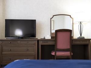 1 dormitorio con escritorio, TV y silla en Ariston Hotel Kobe en Kobe