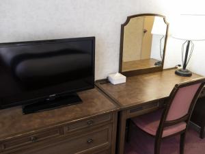 a desk with a television and a mirror on it at Ariston Hotel Kobe in Kobe