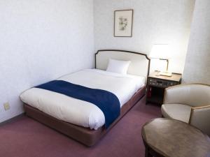 a hotel room with a bed and a chair at Ariston Hotel Kobe in Kobe