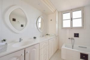 a white bathroom with two sinks and a tub and a mirror at ALEXANDRE MAISON Beachfront Gialova Vacation Home in Gialova