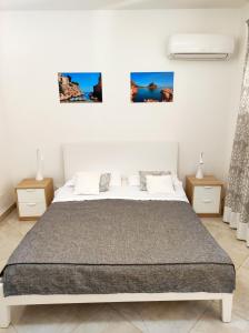 a white bedroom with a bed and three pictures on the wall at B&B Flavilla in Santa Flavia