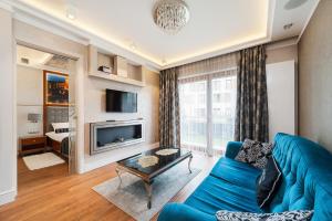 a living room with a blue couch and a tv at ApartmentPrestige Central Station in Kraków