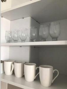 una fila di bicchieri da vino e tazze su uno scaffale di Apartments GC 3 a Rafailovici