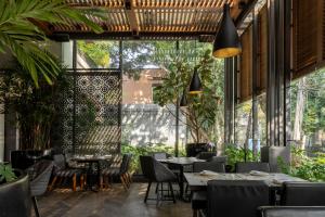 - un restaurant avec des tables, des chaises et de grandes fenêtres dans l'établissement Brick Hotel Mexico City - Small Luxury Hotels of the World, à Mexico