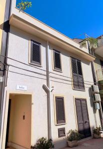 a white building with black shutters on it at B&B Flavilla in Santa Flavia