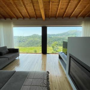 a living room with a couch and a large window at Casa do Afonso in Brufe