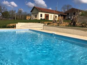 a large blue swimming pool in front of a house at Walnut Lodge Espas 2 bedroom, Barn Conversion in Espas