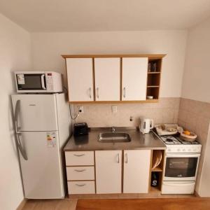 a kitchen with a white refrigerator and a sink at L&B departamento premium céntrico II Jujuy in San Salvador de Jujuy