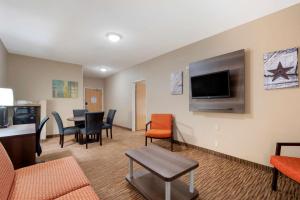 a living room with a table and chairs and a flat screen tv at Best Western Plus DFW Airport Suites in Irving
