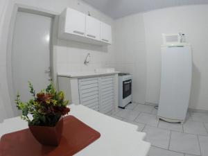- une cuisine blanche avec un réfrigérateur blanc et une table dans l'établissement Morada da Lena 1, à Balneário Camboriú
