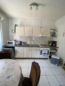 uma cozinha com armários brancos e uma mesa com cadeiras em Toni&Megi Apartment em Jesenice
