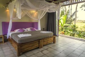 a bedroom with a large bed with a canopy at Prashanti Bali in Ubud