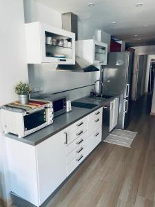 una cocina con armarios blancos y electrodomésticos de acero inoxidable en Fantastic Apartment City Center - Optional Parking, en Málaga
