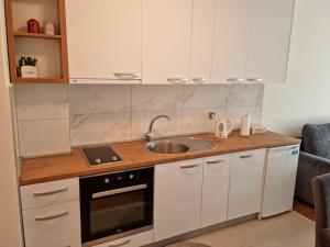 a kitchen with white cabinets and a sink at apartman Kami in Tuzla