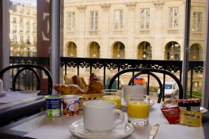 波爾多的住宿－劇院酒店，一张桌子,早餐包括咖啡和橙汁