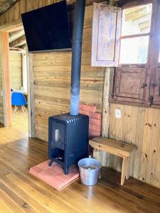 a wood stove in a room with a wooden wall at Pousada Flor de Lótus dos Canyons in Praia Grande
