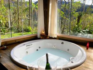 uma grande banheira num quarto com janelas em Pousada Flor de Lótus dos Canyons em Praia Grande