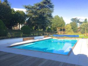 een zwembad in een tuin met een houten terras bij Domaine des Grands Cèdres in Cordelle