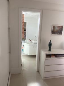 ein weißes Badezimmer mit einem Waschbecken und einem Spiegel in der Unterkunft Apartamento de luxo, 3 quartos, Cabo Frio-RJ in Cabo Frio