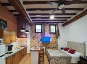 a kitchen and a bedroom with a bed and a tv at LA MUNTANYA - Apartamentos Rural Guadalest in Benimantell