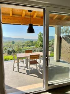 una puerta de cristal que da a un patio con mesa y sillas en Villa Boni, en Costermano