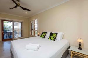 een slaapkamer met een wit bed en een plafondventilator bij Sovereign Hill Country Villa in Lovedale