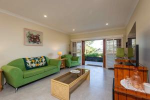 een woonkamer met een groene bank en een tv bij Sovereign Hill Country Villa in Lovedale