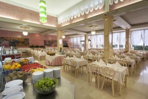 a restaurant with white tables and chairs and fruit on tables at Hotel Istra Plava Laguna in Poreč