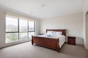 a bedroom with a bed and a large window at Holiday Rental 6 KING BD 12PPL in Truganina