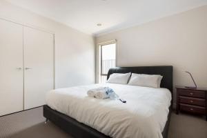um quarto com uma grande cama branca e uma cómoda em Holiday Rental 6 KING BD 12PPL em Truganina