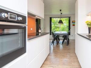 a kitchen with white cabinets and a dining room with a table at 8 person holiday home in Hemmet in Falen