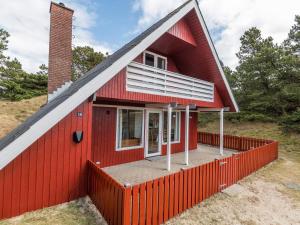 une maison rouge entourée d'une clôture rouge dans l'établissement Holiday home Fanø XLIV, à Fanø