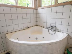 a bath tub in a tiled bathroom with a window at Tranquil Oasis in Rindby in Fanø +19 photos