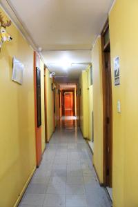 a long hallway with yellow walls and a tile floor at HOSTAL JUMI in Tacna