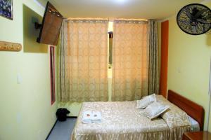 a small bedroom with a bed and a window at HOSTAL JUMI in Tacna