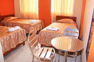 a room with two beds and a table and chairs at HOSTAL JUMI in Tacna