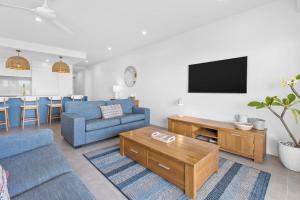 陽光海灘的住宿－6 Seabreeze Spacious Newly Renovated Apartment with Ocean Views，客厅配有蓝色的沙发和电视
