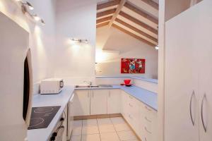 a small kitchen with white cabinets and a sink at 7 Depper Cosy Beach House in Central Sunshine Beach in Sunshine Beach