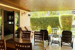 a patio with a table and chairs on a porch at Family-friendly house, a few steps from the pool and close to the ocean. in Mae Pim