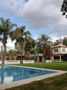 a swimming pool in front of a house with palm trees at Finca el Nogal - Casa Entera Familiar Moderna con Amplio Jardín Atlixco puebla in Atlixco