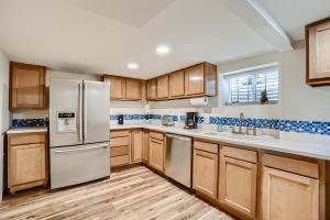 una cocina con armarios de madera y electrodomésticos de acero inoxidable en Sloans Lake Getaway Near Broncos & Downtown Denver, en Lakewood