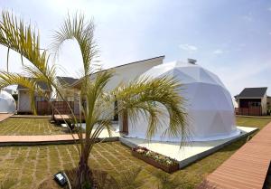 ein weißes Kuppelhaus mit einer Palme im Hof in der Unterkunft Ducale Garden Hotel Kujukuri in Kujukuri